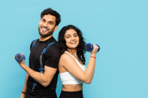 Fitness Couple Exercising With Weights On Blue Background Showing Strength and Team Work In Active Lifestyle Concept
